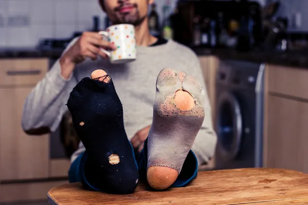 Man with worn out socks having coffee in kitchen Royalty Free Stock Images