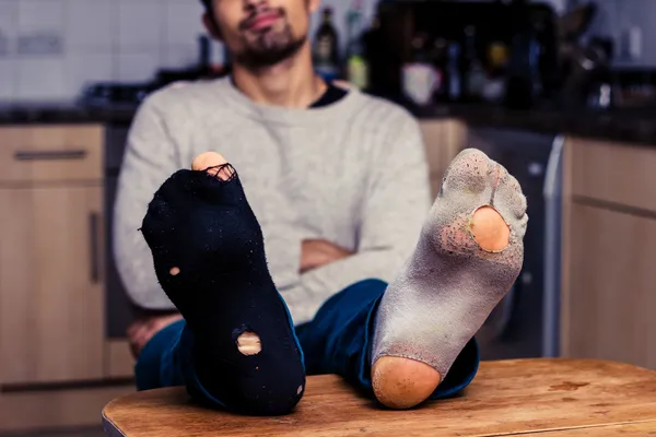 Man with worn out socks relaxing in kitchen Stock Photo