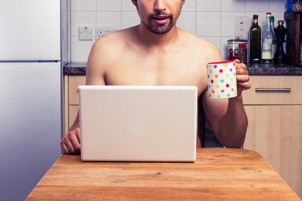 Naked man at home with laptop and coffee