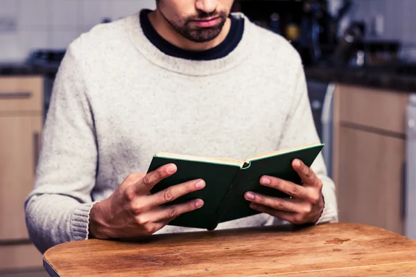 Young man reading in his kitchen — Stock Photo, Image