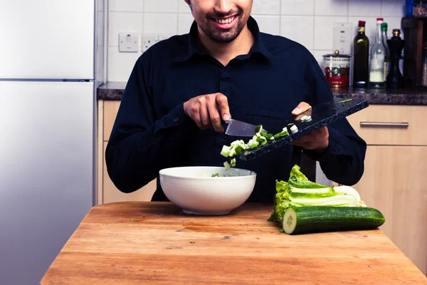 Feliz hombre mezclando una ensalada en la cocina —  Fotos de Stock