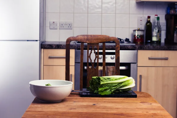 Table de cuisine avec planche à découper et salade — Photo