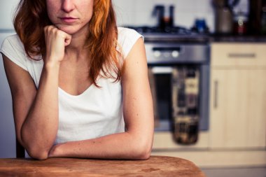 Woman is thinking in her kitchen clipart