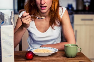 Kahvaltıda tahıl ve meyve olan genç bir kadın