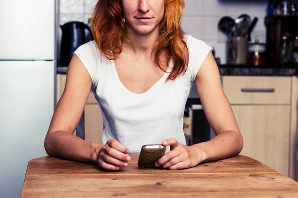 Женщина пользуется телефоном на кухне — стоковое фото