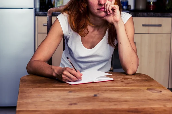 Gelangweilte Frau schreibt in ihrer Küche — Stockfoto