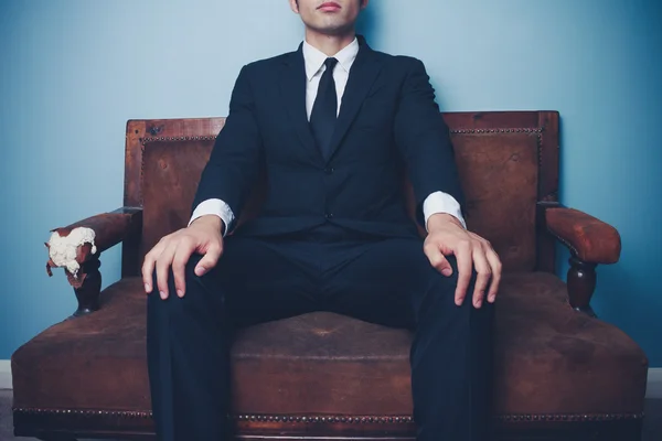 Jonge zakenman op sofa in krachtige pose — Stockfoto