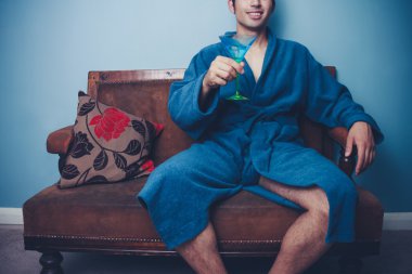 Young playboy in dressing gown toasting with cocktail clipart