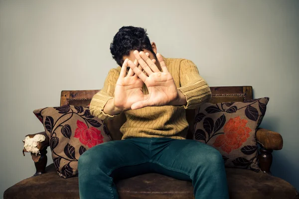 Joven en sofá cubriéndose la cara —  Fotos de Stock