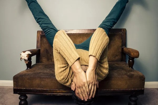 Hombre joven cansado está boca abajo en el sofá viejo — Foto de Stock