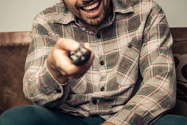 Happy man watching television and changing the channel — Stock Photo, Image