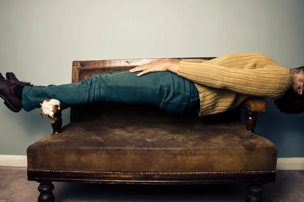 Young man in plank position on old sofa — Stock Photo, Image