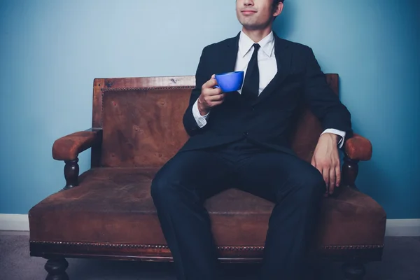 Молодой бизнесмен на диване пьет кофе — стоковое фото