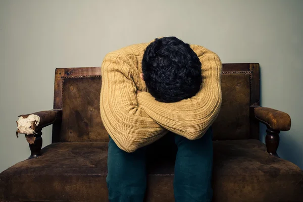 Deprimido homem sentado no sofá velho — Fotografia de Stock