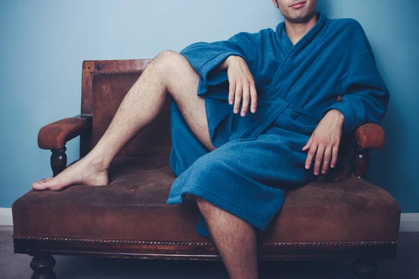 Junger Mann in Robe posiert auf Vintage-Sofa — Stockfoto