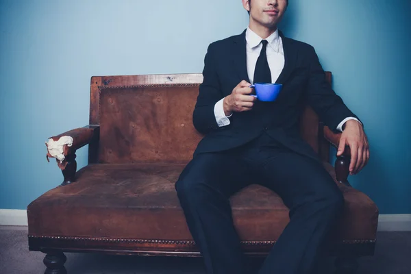 Businessman on old vintage sofa drinking coffee — Stock Photo, Image