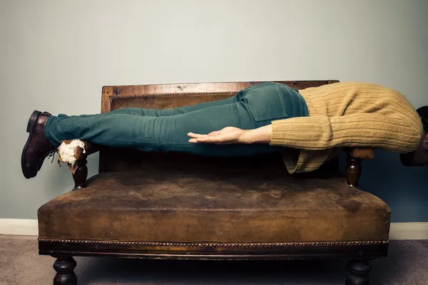 Молодой человек в положении доски на старом диване — стоковое фото
