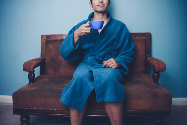 Mannen i morgonrock dricka kaffe på vintage soffa — Stockfoto