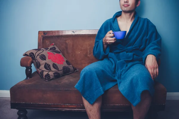 Joven bebiendo de la taza en el sofá vintage — Foto de Stock