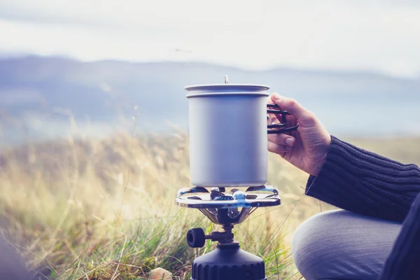 Mujer agua hirviendo en estufa de camping portátil — Foto de Stock