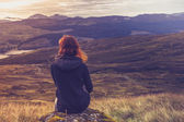Woman sitting on mountain top and contemplating