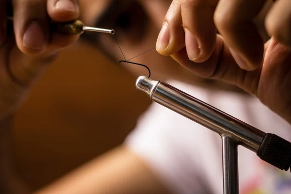 Close up on young man's hands tying a fly for fishing — Stock Photo, Image