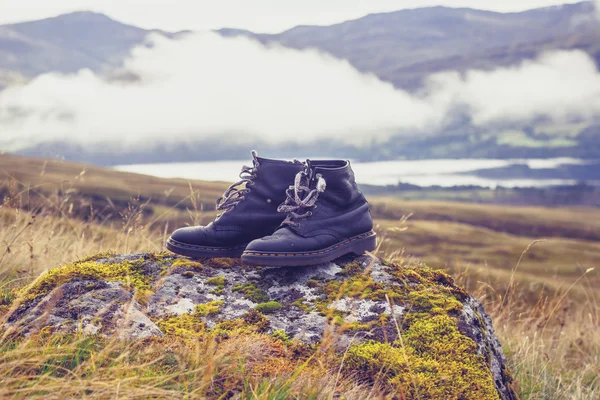 Paar zwarte van oude lopen laarzen op een rots in de bergen — Stockfoto
