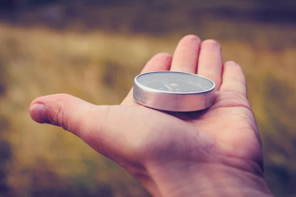 Hand holding a compass in the wilderness — Stock Photo, Image