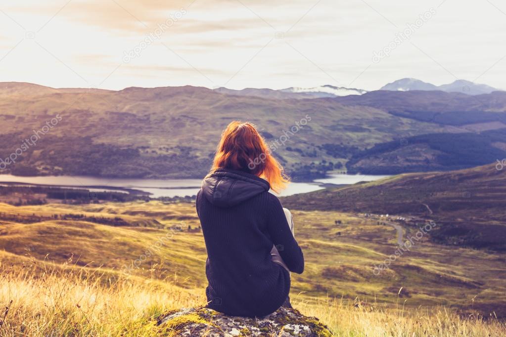 Woman looking at the sunset over mountains