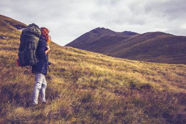 Woman with backpack about to climb mountain clipart