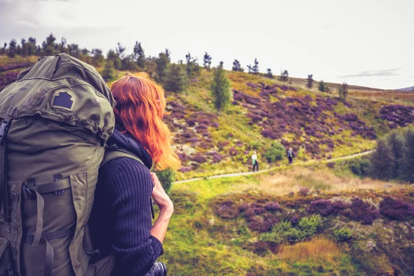 距離で仲間の hillwalkers を見てのバックパックを持つ女性 — ストック写真