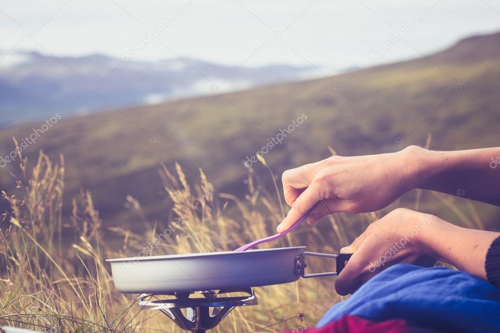 Close up on hands cooking on portable stove in the wild