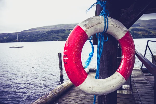 Life buoy hanging on pier at lake — Stock Photo, Image