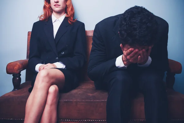 Nervöser Geschäftsmann sitzt neben selbstbewusster Geschäftsfrau — Stockfoto