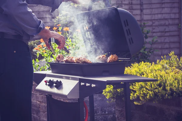 Muž vaření masa na grilování venku — Stock fotografie