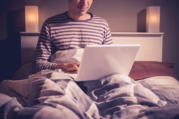 Giovane uomo seduto a letto video chat — Foto Stock