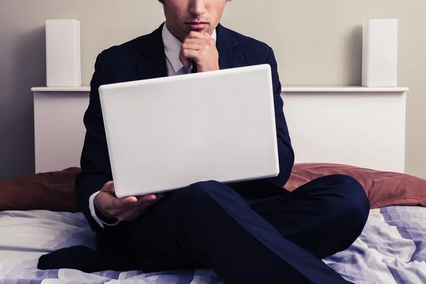 Jovem empresário sério trabalhando no laptop no quarto de hotel — Fotografia de Stock