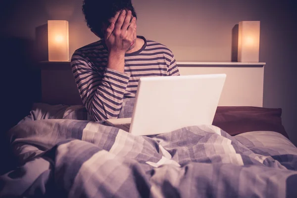 Verdrietig man in bed met laptop — Stockfoto