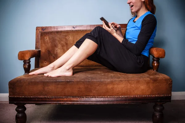 Jovem mulher sentada no sofá usando um tablet — Fotografia de Stock