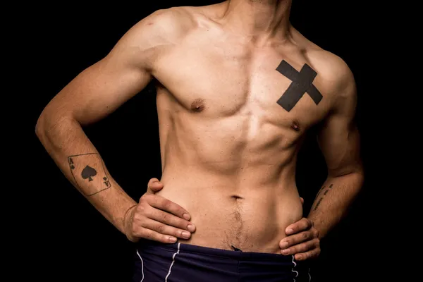 Young athletic shirtless man posing on black background — Stock Photo, Image