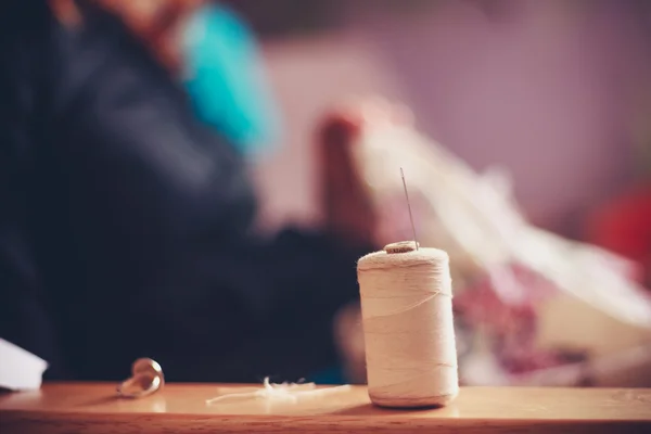 Thread and sewing equipment with woman in background — Stock Photo, Image