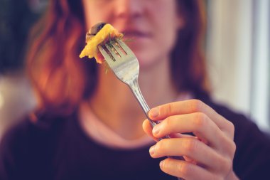 Yemek çatalı yüzünün önünde tutan kadın
