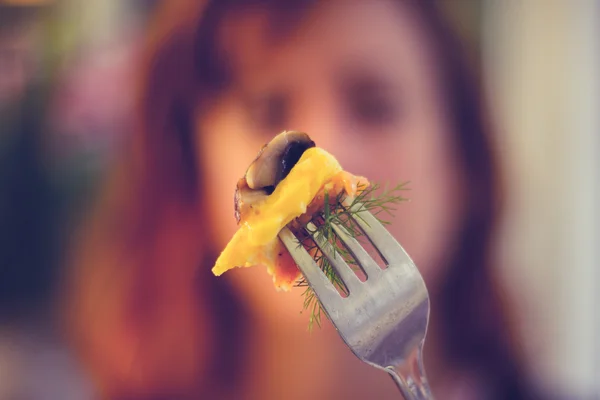 Mulher segurando um garfo com comida na frente do rosto — Fotografia de Stock