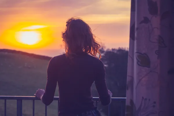 Žena obdivující západ slunce z balkónu — Stock fotografie