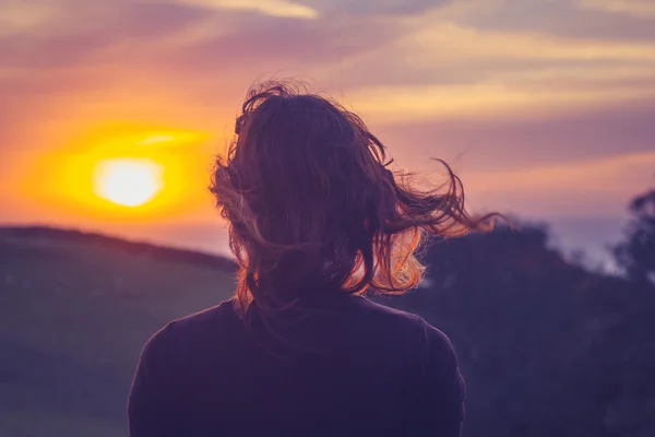 Jeune femme admirant le coucher du soleil sur les champs — Photo