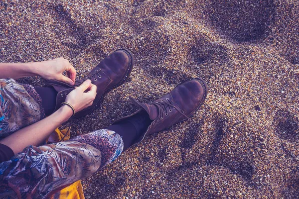 Mujer atando sus cordones de botas en la playa — Foto de Stock