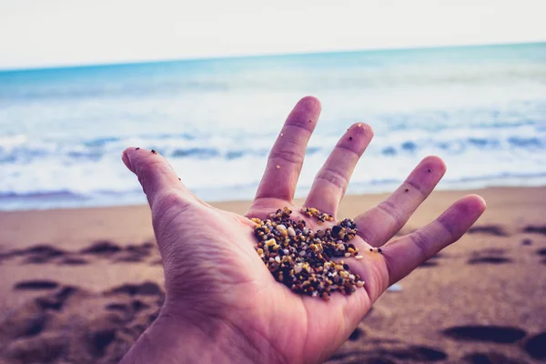 Man's open hand at beach with pebbles — Stock Photo, Image