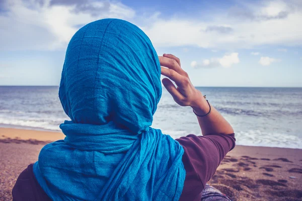 Bakifrån med kvinna med huvudduk tittar på havet — Stockfoto