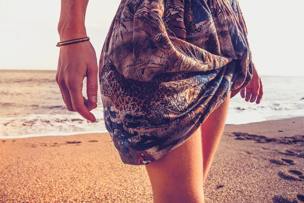 Ung kvinna i färgglada kjol promenerar på stranden — Stockfoto