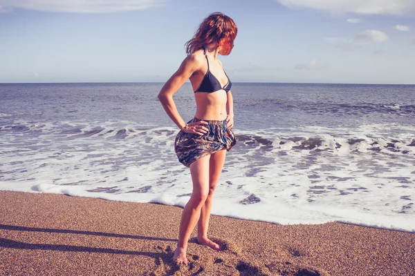 Bela jovem mulher de pé na praia — Fotografia de Stock